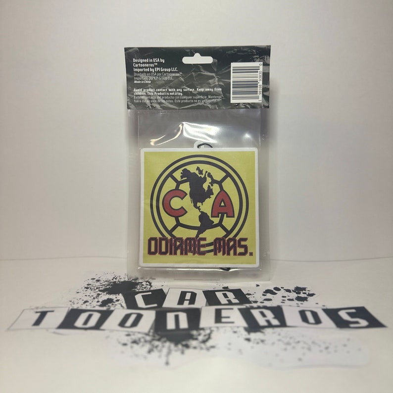 May include: A yellow and red car air freshener with a soccer ball design and the text "ODIRME-MAS." The air freshener is packaged in a clear plastic bag with a white background.