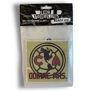 May include: A yellow and black car air freshener with the words "CAR TOONEROS" and "BLACK ICE" printed on the top. The air freshener features a red and black soccer logo with the letters "CA" and the words "ODIAME-MAS."