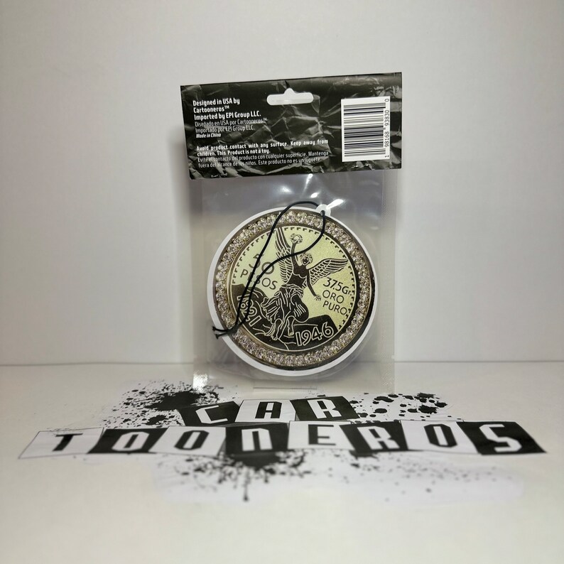 Pu&ograve; includere: Un profumatore per auto dorato a forma di moneta messicana da 50 pesos con la scritta "37.5G ORO PURO 1946" e la raffigurazione di un angelo. Il profumatore &egrave; circondato da un anello di strass.