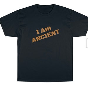 May include: A black t-shirt with the text "I Am Ancient" printed in brown on the front.
