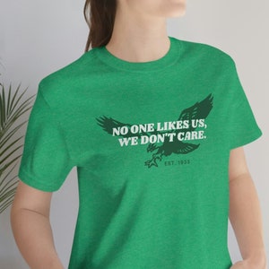 May include: Green t-shirt with a black and white eagle graphic and the text "NO ONE LIKES US, WE DON'T CARE. EST. 1933"