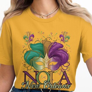 NOLA Tシャツ、ニューオーリンズグラフィックTシャツ、マルディグラマスクデザイン、フルール・ド・リスのお祝い、ルイジアナのお土産、パーティー衣装