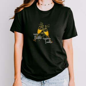 May include: Black t-shirt with a gold graphic of two champagne glasses clinking. The text "Hello Bubbles Goodbye Trouble" is printed on the shirt.