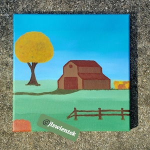 Op de afbeelding: Een vierkant canvas schilderij toont een landelijk landschap met een bruine schuur, een grote gele boom en een houten hek tegen een helderblauwe lucht. Het schilderij toont een groen veld en bevat de tekst jlswientek in de benedenhoek.