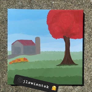 Op de afbeelding: Een vierkant schilderij op canvas toont een landelijk landschap met een grijze schuur met een rood dak en een silo. Een grote boom met een felrode kroon staat aan de rechterkant. De scène bevat een groen veld, een blauwe lucht en de tekst jlswientek.