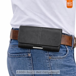 May include: Black leather belt case with a silver-colored metal clasp, worn on a brown belt over blue jeans. The case has a stitched design and the text "(WC)". The image also includes the text "2,000+ Sold | Belt Carry Design".