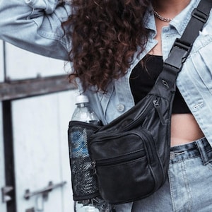 May include: Black leather fanny pack with a water bottle holder. The pack has a zippered main compartment and a smaller front pocket. The water bottle holder is made of black mesh. The bag is worn across the body.