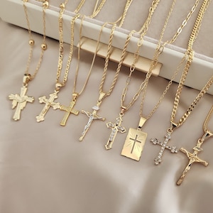 May include: A set of nine gold chain necklaces with different cross pendants. The crosses are all gold and have various designs, including a simple cross, a cross with a crown, and a cross with a heart.