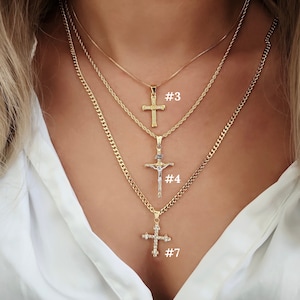 May include: Three gold chain necklaces with different cross pendants. The top pendant is a simple cross, the middle pendant is a crucifix, and the bottom pendant is a jeweled cross. The necklaces are labelled #3, #4, and #7.