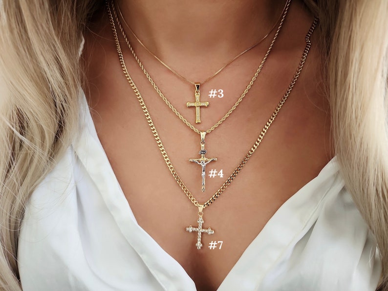 May include: Three gold chain necklaces with different cross pendants. The top pendant is a simple cross, the middle pendant is a crucifix, and the bottom pendant is a jeweled cross. The necklaces are labelled #3, #4, and #7.
