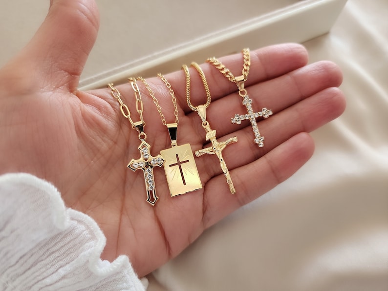 May include: Four gold necklaces with different cross pendants. Each cross is adorned with clear rhinestones. The crosses are on a chain with a lobster clasp.