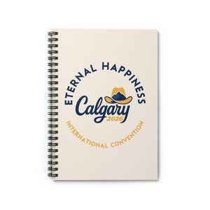 Op de afbeelding: Een spiraalgebonden notitieboek met een crèmekleurige kaft. De kaft toont de tekst "Eternal Happiness Calgary 2026 International Convention" in marineblauw en goud, met een cowboyhoed.