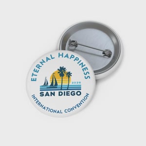 Puede incluir: Dos botones redondos blancos con respaldo de alfiler metálico. El botón frontal presenta un diseño con el texto "Eternal Happiness" y "San Diego International Convention 2026". El diseño incluye una puesta de sol, veleros y palmeras.