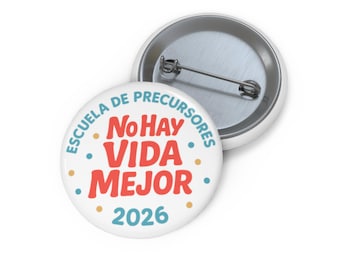 May include: White button pin with the text "ESCUELA DE PRECURSORES No HAY VIDA MEJOR 2026" in red and blue. The pin has a metal back and a safety pin clasp. The button is round and has a glossy finish.