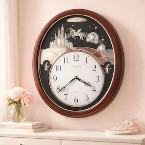 May include: A decorative wall clock with a dark brown wooden frame. The clock face is white with black numerals and hands. The upper portion features a silver-toned fantasy scene with a castle, carriage, and dragon. The clock reads "Small World" and "needt".