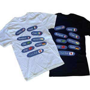 May include: Two t-shirts, one white and one black, with the word "Hello" in different languages printed on them. The languages include English, Spanish, Italian, French, Portuguese, Hindi, German, Chinese, and Japanese.