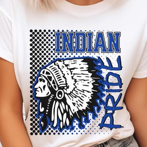 Op de afbeelding: Wit T-shirt met een blauw en zwart grafisch ontwerp. Het ontwerp toont de woorden "INDIAN PRIDE" en een zwart-wit illustratie van een Indiaanse chef. Het ontwerp bevat een stippenpatroon.