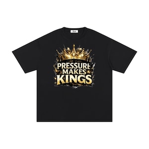 Puede incluir: Camiseta negra con un diseño de corona dorada y el texto "PRESSURE MAKES KINGS". El diseño está centrado en la parte delantera. La camiseta está hecha de un material suave y cómodo.
