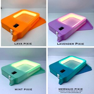 K&ouml;nnte beinhalten: Vier farbenfrohe, rechteckige Leuchten mit leuchtendem Innenraum und einem kleinen Schalter. Die Farben sind Orange, Lila, Mintgr&uuml;n und T&uuml;rkis. Jede Leuchte tr&auml;gt die Aufschrift: "LAVA PIXIE", "LAVENDER PIXIE", "MINT PIXIE" und "MERMAID PIXIE".