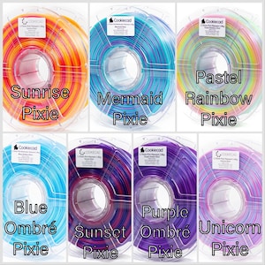 K&ouml;nnte beinhalten: Eine Auswahl an 3D-Drucker-Filamentrollen in verschiedenen Farben. Die Rollen sind mit "Sunrise Pixie", "Mermaid Pixie", "Pastel Rainbow Pixie", "Blue Ombre Pixie", "Sunset Pixie", "Purple Ombre Pixie" und "Unicorn Pixie" beschriftet.
