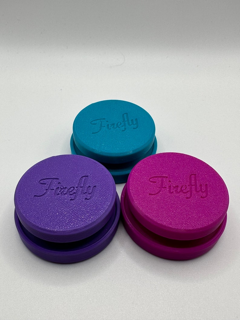 Puede incluir: Tres recipientes redondos apilables con la palabra "Firefly" en relieve en la parte superior. Los recipientes son de color turquesa, morado y rosa.