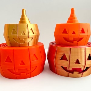 Pu&ograve; includere: Un set di tre decorazioni di Halloween a forma di zucca impilate, di colore arancione e dorato. La zucca in cima &egrave; dorata, quella nel mezzo &egrave; arancione e quella in fondo &egrave; dorata.