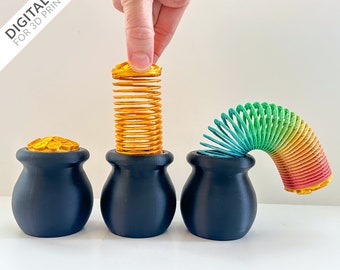 May include: Three black pots with gold coin lids, each holding a different colored spring toy. The first pot has a gold spring, the second has a rainbow spring, and the third has a green spring.