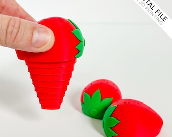 Puede incluir: Un tapón de botella rojo con forma de fresa y hojas verdes es sostenido. Dos tapones más con forma de fresa están sobre una superficie blanca. La imagen incluye el texto "DIGITAL FILE FOR 3D PRINTING".