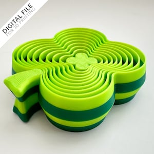 Può includere: Un tagliapasta a forma di trifoglio a più strati, di colore verde e verde scuro. Il tagliapasta è in plastica e presenta un design a strisce.