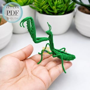 May include: A bright green crocheted praying mantis figurine with articulated legs and antennae. The insect features a detailed textured surface created by fine yarn stitches. A circular graphic in the upper left corner displays the text PATTERN PDF ENGLISH.