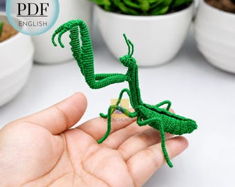 May include: A bright green crocheted praying mantis figurine with articulated legs and antennae. The insect features a detailed textured surface created by fine yarn stitches. A circular graphic in the upper left corner displays the text PATTERN PDF ENGLISH.