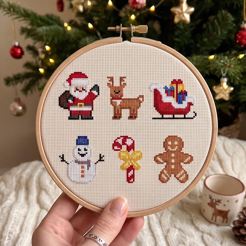 Pu&ograve; includere: Un telaio da ricamo circolare in legno contenente un motivo a punto croce su tessuto color crema. Il design presenta sei icone natalizie: Babbo Natale, una renna, una slitta rossa con regali, un pupazzo di neve, un bastoncino di zucchero e un omino di pan di zenzero.