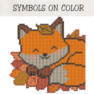 May include: A cross-stitch pattern chart featuring a fox design with the text SYMBOLS ON COLOR at the top. The fox is composed of a grid of squares filled with numbers and symbols representing different colors, primarily orange, white, and brown.