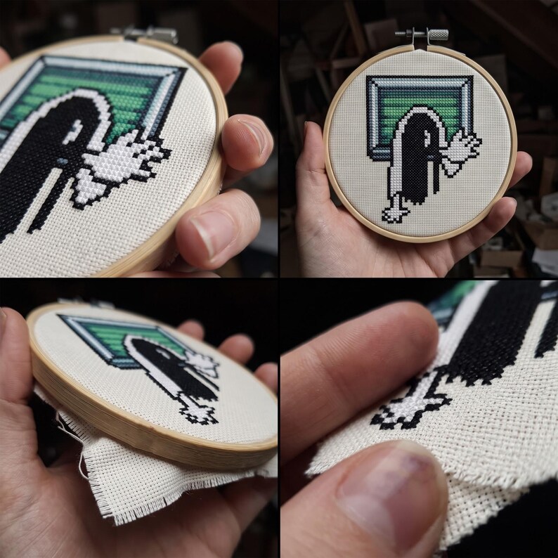 K&ouml;nnte beinhalten: Ein runder Stickrahmen aus Holz mit einer Kreuzsticharbeit auf wei&szlig;em Stoff. Das Motiv zeigt eine verpixelte schwarz-wei&szlig;e Figur mit ausgestreckten H&auml;nden, die aus einem gr&uuml;n-grauen, rechteckigen Fensterrahmen hervorkommt.