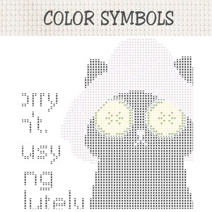 May include: A cross-stitch pattern chart titled COLOR SYMBOLS featuring a grid layout with black, grey, and light green symbols. The design depicts a stylised animal figure with large eyes, using various alphanumeric characters and shapes.
