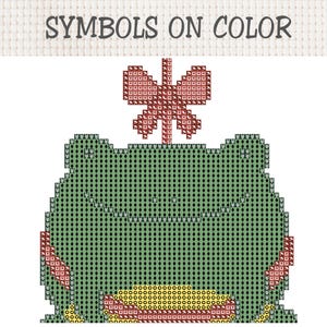 May include: A cross-stitch pattern featuring a green frog with a red butterfly on its head and a yellow belly. The design is composed of various geometric symbols on a grid, with the text SYMBOLS ON COLOR displayed at the top of the image.