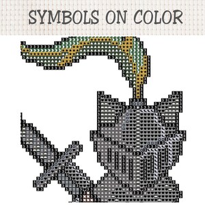 Op de afbeelding: Een kruissteekpatroon getiteld SYMBOLS ON COLOR met een ridderhelm met een pluim en een zwaard. Het ontwerp bestaat uit een raster van zwarte vierkantjes met diverse symbolen zoals cijfers, letters, sterren en hartjes voor de draadkleuren.