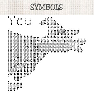 Op de afbeelding: Een kruissteekpatroon op witte Aida-stof met het woord SYMBOLS bovenaan. Daaronder staat het woord You in zwarte stippen. Een grote heksenhoedvorm is gevuld met diverse zwarte symbolen en letters, waaronder N, Z en b&egrave;ta-tekens.