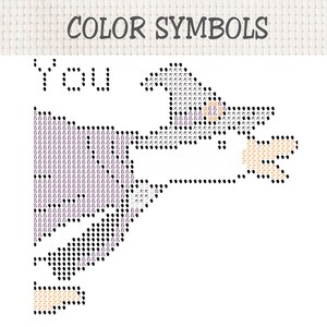 Op de afbeelding: Een kruissteekpatroon met de titel COLOR SYMBOLS, voorzien van het woord You en het silhouet van een heks. Het ontwerp gebruikt zwarte, paarse en beige symbolen op een wit raster om de kleuren van het borduurgaren aan te duiden.