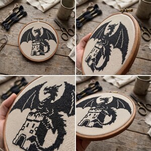 Peut inclure: Un tambour &agrave; broder circulaire en bois contenant un ouvrage au point de croix sur un tissu couleur cr&egrave;me. Le motif repr&eacute;sente la silhouette noire d'un dragon perch&eacute; au sommet d'une tour en pierre. La broderie est tendue dans le cadre.