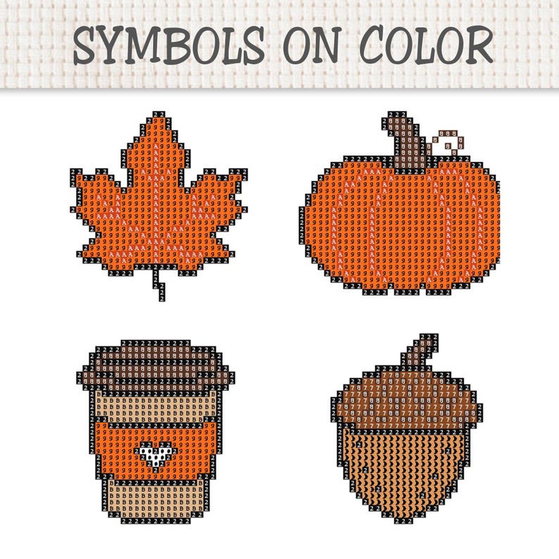 May include: A cross-stitch pattern sheet titled SYMBOLS ON COLOR featuring four autumn-themed designs: a maple leaf, a pumpkin, a coffee cup, and an acorn. Each icon is composed of a grid of colored squares filled with alphanumeric symbols.