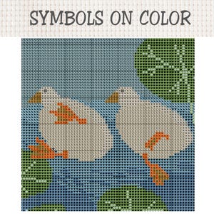 K&ouml;nnte beinhalten: Eine Kreuzstichvorlage mit der &Uuml;berschrift SYMBOLS ON COLOR, die zwei wei&szlig;e Enten auf blauem Wasser mit gr&uuml;nen Seerosen zeigt. Das Design verwendet ein Raster aus Buchstaben und Symbolen, um die Garnfarben f&uuml;r Enten und Wasser anzugeben.