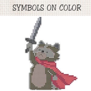 Pu&ograve; includere: Uno schema a punto croce intitolato SYMBOLS ON COLOR che raffigura un orso pixelato che tiene in alto una spada. L'orso &egrave; reso in tonalit&agrave; di grigio e marrone con una sciarpa o mantello rosso, composto da vari simboli su una griglia.
