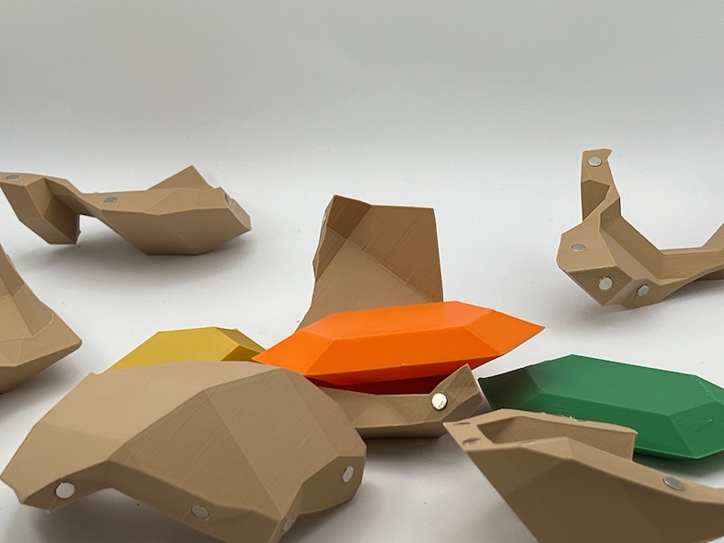 Pu&ograve; includere: Un set di forme geometriche in plastica marrone, arancione, gialla e verde. Le forme sono progettate per incastrarsi come un puzzle.