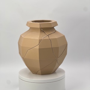 Pu&ograve; includere: Un vaso in ceramica beige con un design geometrico e crepe su tutta la superficie. Il vaso &egrave; posto su un piedistallo bianco.