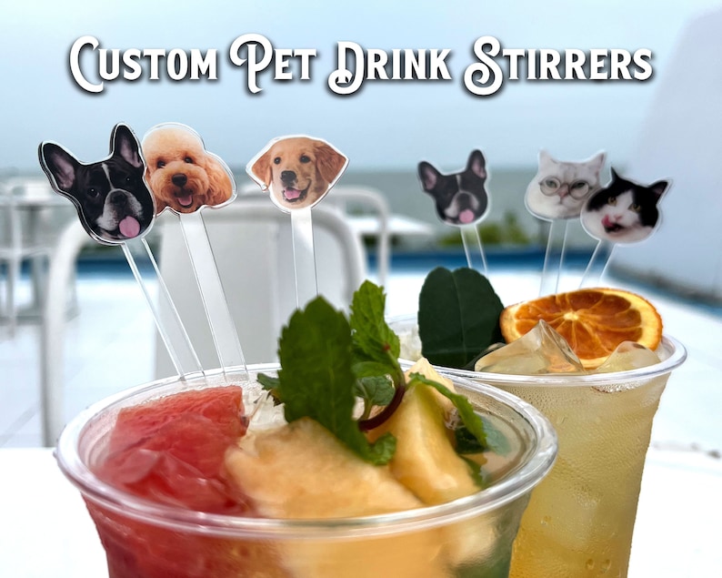 May include: Clear acrylic drink stirrers featuring custom pet face cutouts, including dogs and cats. The text "CUSTOM PET DRINK STIRRERS" is displayed at the top. These stirrers are placed inside two plastic cups filled with fruit-infused beverages.