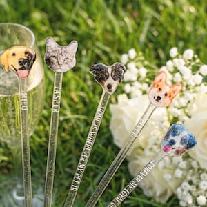 May include: Five clear drink stirrers with pet-themed designs. Each stirrer features a different pet face: a yellow lab, a gray cat, a black and white dog, a corgi, and a blue spotted dog. Text on the stirrers reads "Theo", "Jasper", "Home is wherever my pet is", and "Forever my loyal companion".