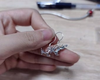 May include: A pair of silver earrings featuring a delicate rabbit design. The earrings are dangle style with a small hoop at the top.