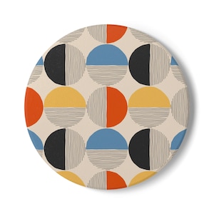 May include: A circular coaster featuring a repeating pattern of circles divided into two halves. Each circle contains a solid color block in blue, black, orange, or yellow, paired with a section of fine black horizontal or vertical lines.