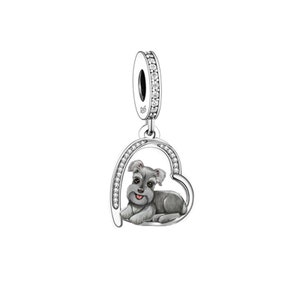 Puede incluir: Encanto de plata con un pequeño perro gris con la nariz rosa dentro de un marco en forma de corazón con cristales transparentes alrededor del borde.